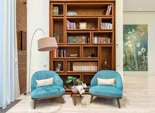 Free Living room with cozy chairs near lamp and wooden bookcase Stock Photo