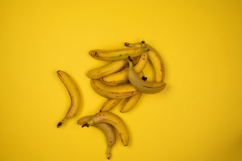 Free From above composition of bunch of fresh ripe bananas on middle of bright yellow surface Stock Photo