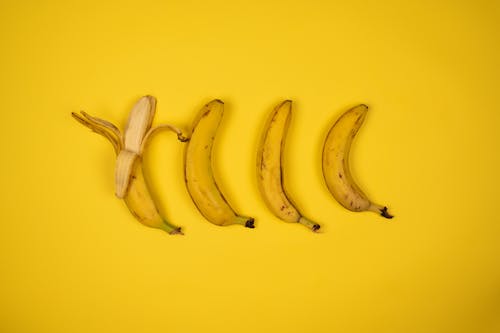 Tasty fresh bananas with peel on yellow background