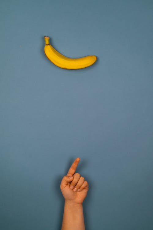 Crop person pointing up against fresh banana