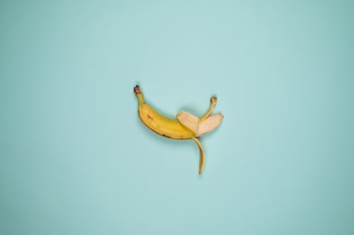 Top view backdrop of tasty whole banana with blots on yellow peel and curved stalk