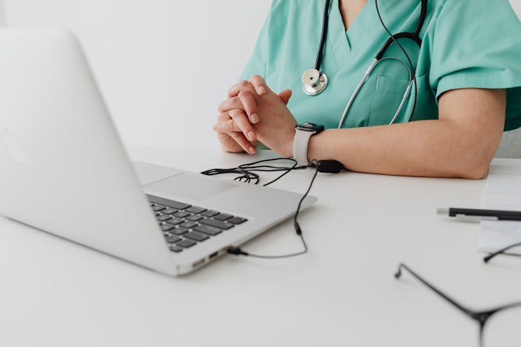 Person In Scrub Suit Using A Silver Laptop 