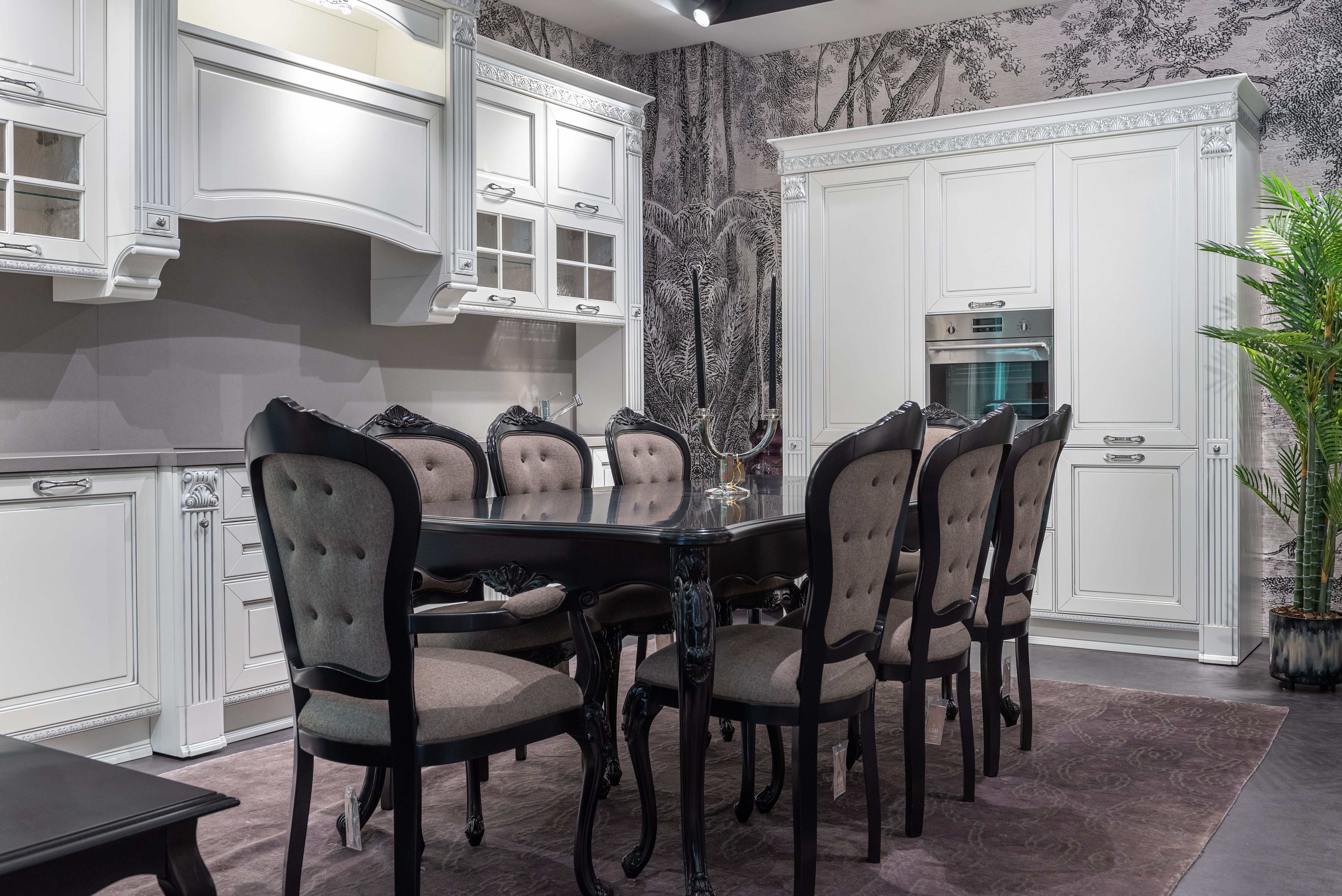 Interior of elegant white and gray kitchen with wooden table and chairs near cabinets against white door