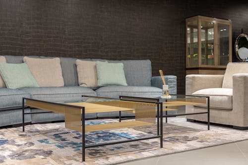 Cozy living room with comfortable gray sofa with cushions and white armchair near modern glass table placed on carpet