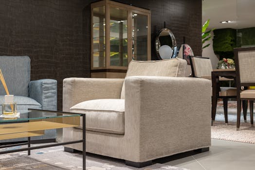 Interior of cozy light living room with comfortable armchairs near table with glass tabletop near cabinet