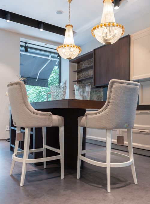 Free Interior of modern dining room with wooden table and white comfortable chairs near cabinets under glowing chandeliers Stock Photo