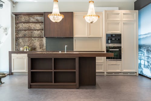 Interior of spacious classic styled kitchen with white and brown wooden furniture and crystal chandeliers