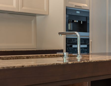 Contemporary kitchen design featuring a sleek chrome faucet on a marble countertop with elegant cabinetry.