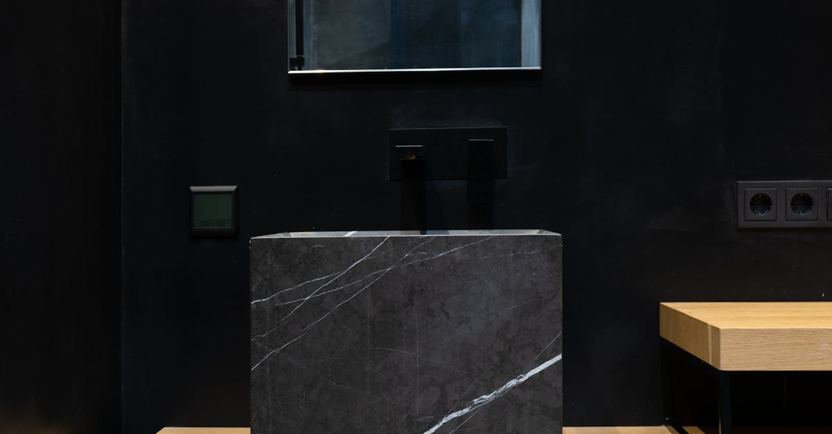 Interior details of modern bathroom with square black marble sink placed on wooden cabinet under mirror hanging on wall