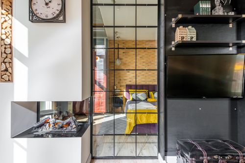 Free Colorful bed with cushions behind glass doorway seen from light modern room with fireplace and shelves with decorations at home Stock Photo