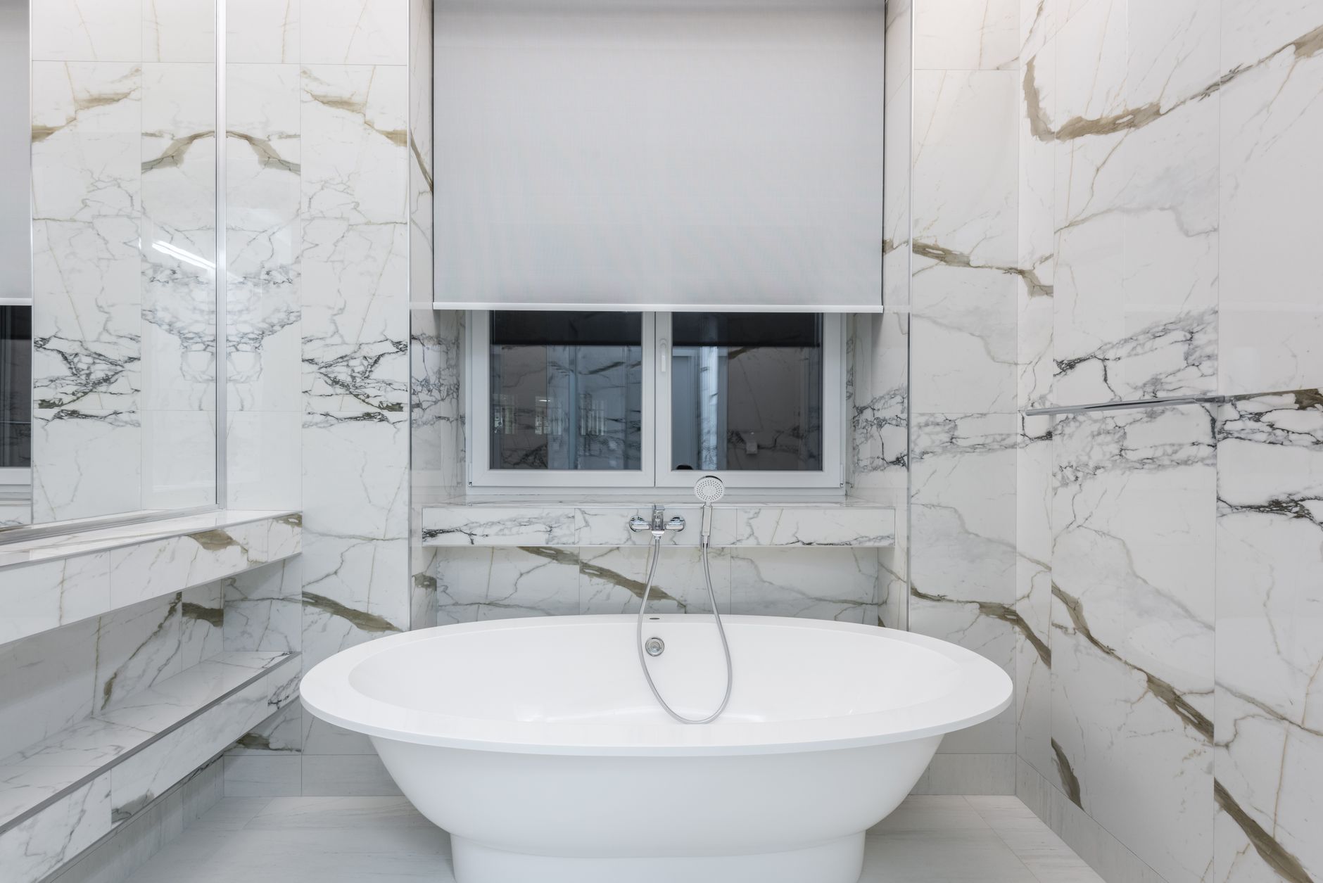 Modern bathroom featuring a luxurious marble design and a sleek freestanding bathtub