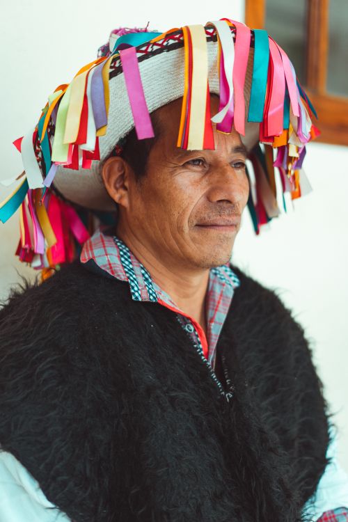 Free Portrait of a man in traditional Mexican attire with vibrant ribbons and poncho. Stock Photo