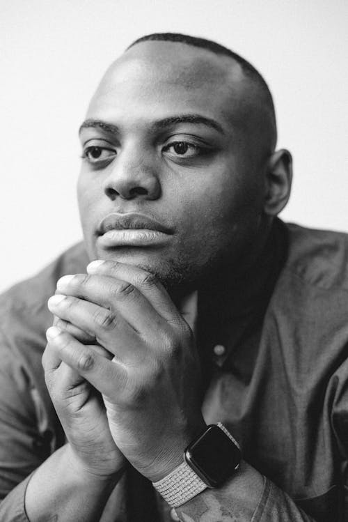 A Grayscale Photo of a Man with His Hands on His Chin