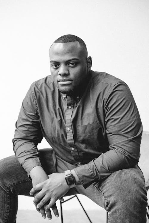 A Man in Black Button Up Long Sleeve Shirt Sitting on a Chair