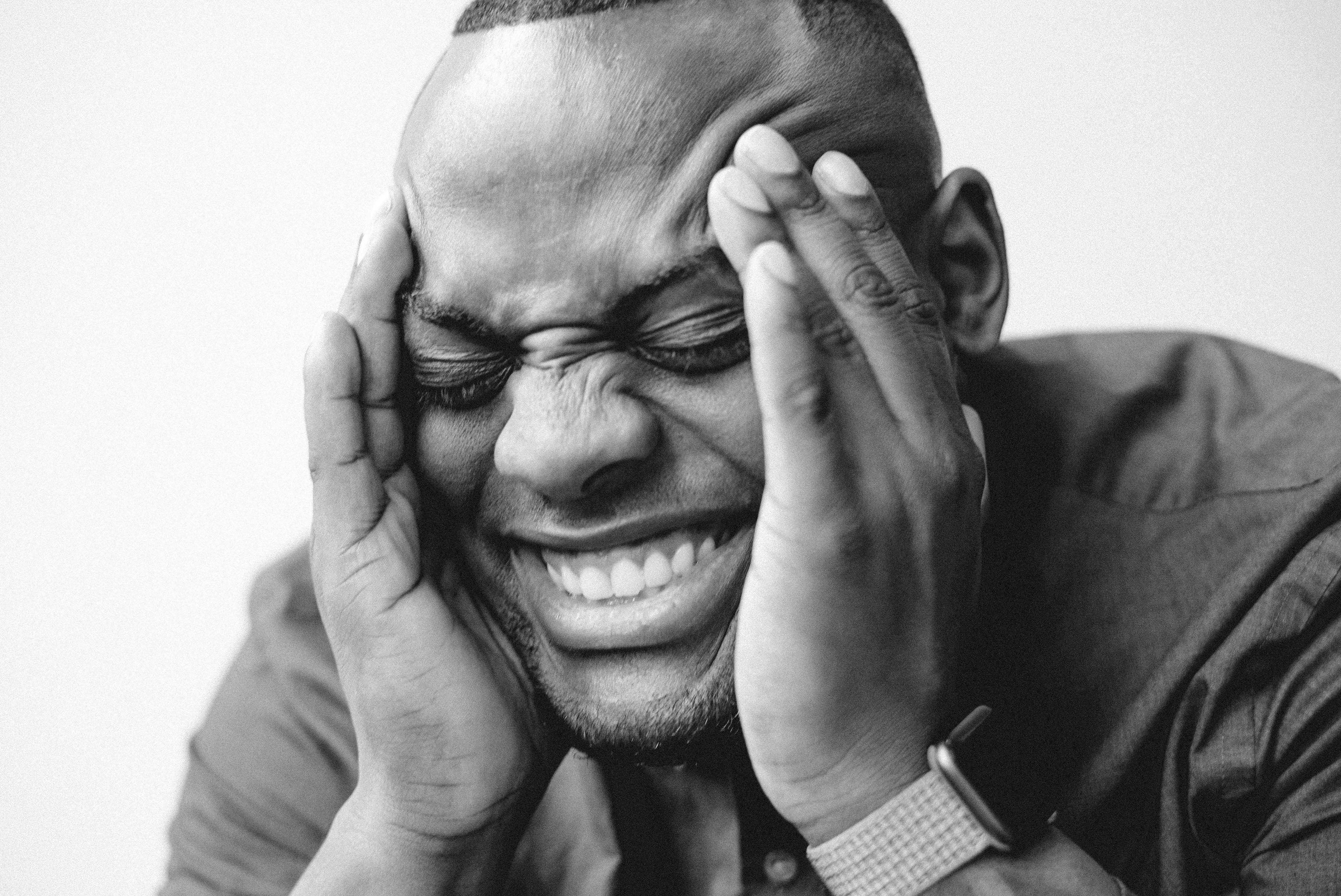 a close up shot of a man smiling with his hands on his head