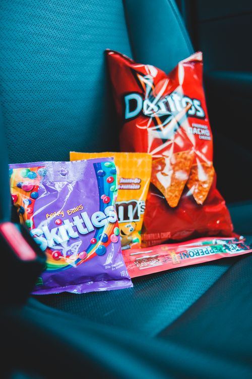 Free Colorful packages with interesting design of different delicious snacks placed on modern car seat in daylight Stock Photo