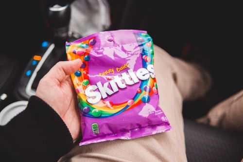 Free From above of crop anonymous person holding candies in colorful packaging while sitting in modern car Stock Photo