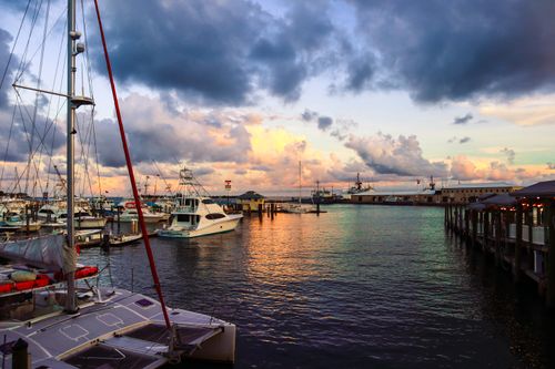 Free A picturesque view of yachts docked at a harbor during sunset, featuring vivid skies and calm waters. Stock Photo