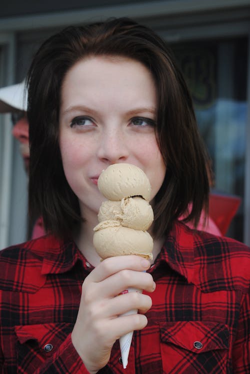 Close-Up Shot of a Woman in Red Plaid Shirt Holding an Ice Cream