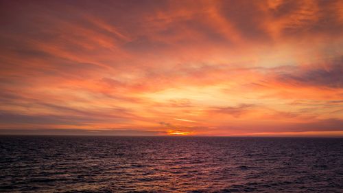 Free Captivating sunset over the ocean with vibrant red and orange hues illuminating the sky. Stock Photo