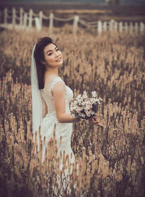 A Woman in White Dress Holding a Bouquet of Flowers