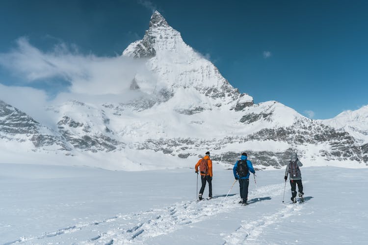 People Hiking On Snow Covered Mountain