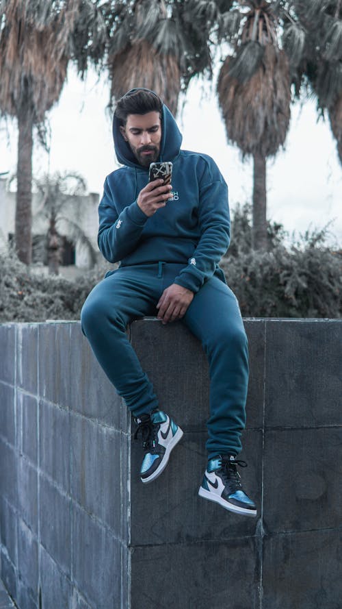 Man Wearing a Hoodie Sweater Sitting on a Plant Box