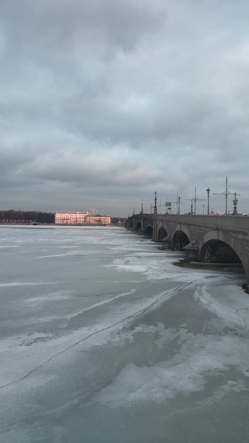 Aged Trinity Bridge crossing frozen Neva river placed in Saint Petersburg in Russia under cloudy sky in daytime