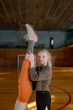 Two girls in a gym practicing gymnastics with enthusiasm and coordination.