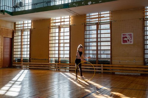 Free A young girl rehearses with a hula hoop in a sunlit gymnasium. Stock Photo