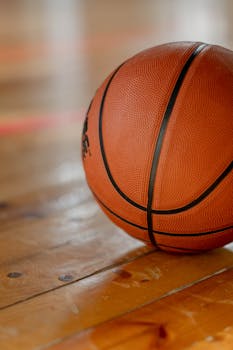 Close-up shot of a basketball on a wooden indoor court floor.