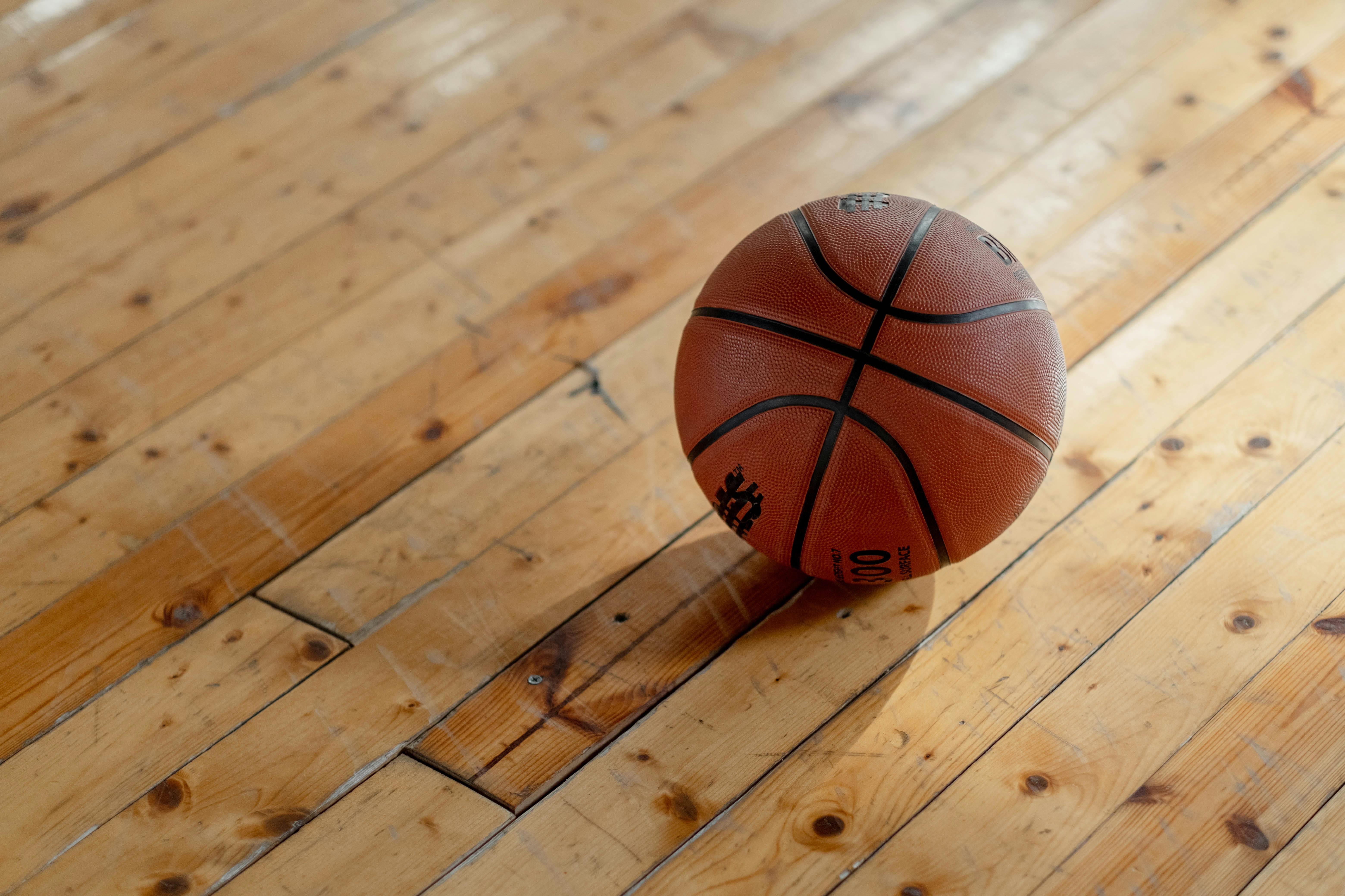 Basketball on a wooden gym floor in a school, highlighting surfaces that require regular cleaning and maintenance in educational facilities.