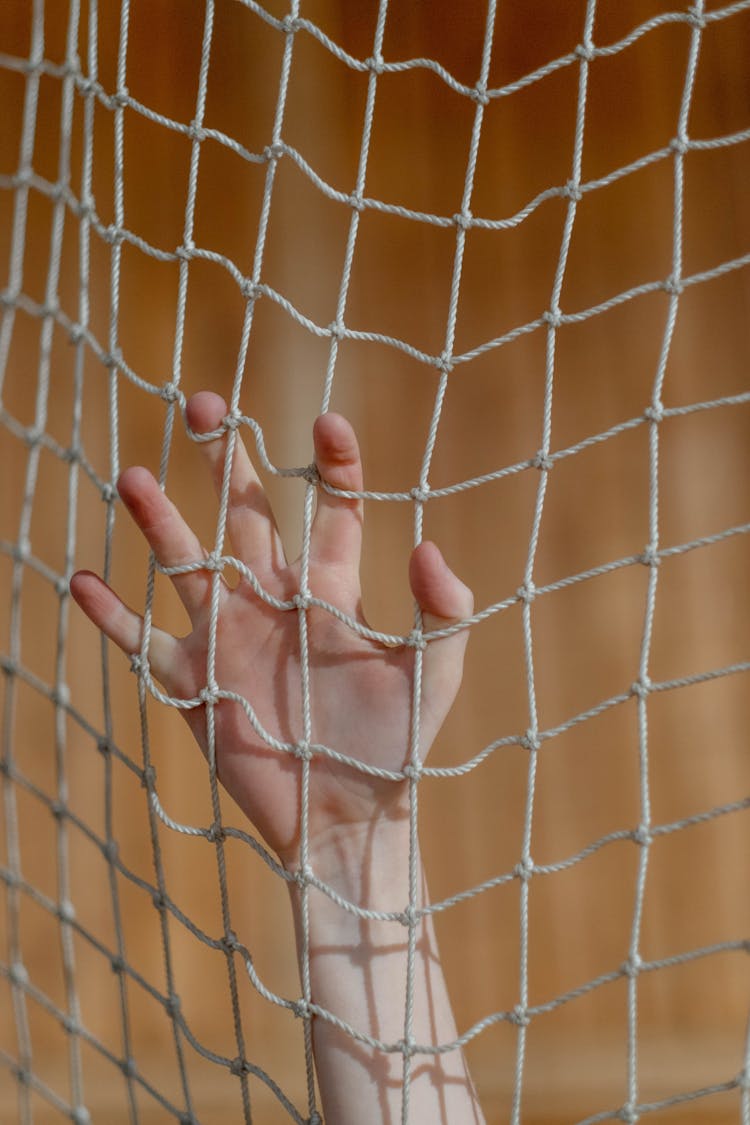 A Hand Clinging On A Net