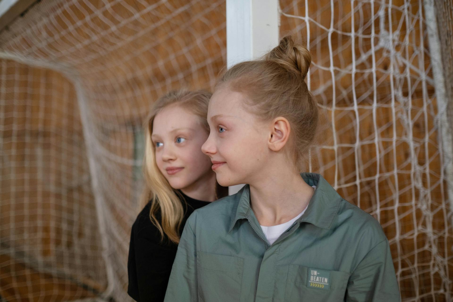 Girls in Black shirt and Green Shirt Standing Beside the Net