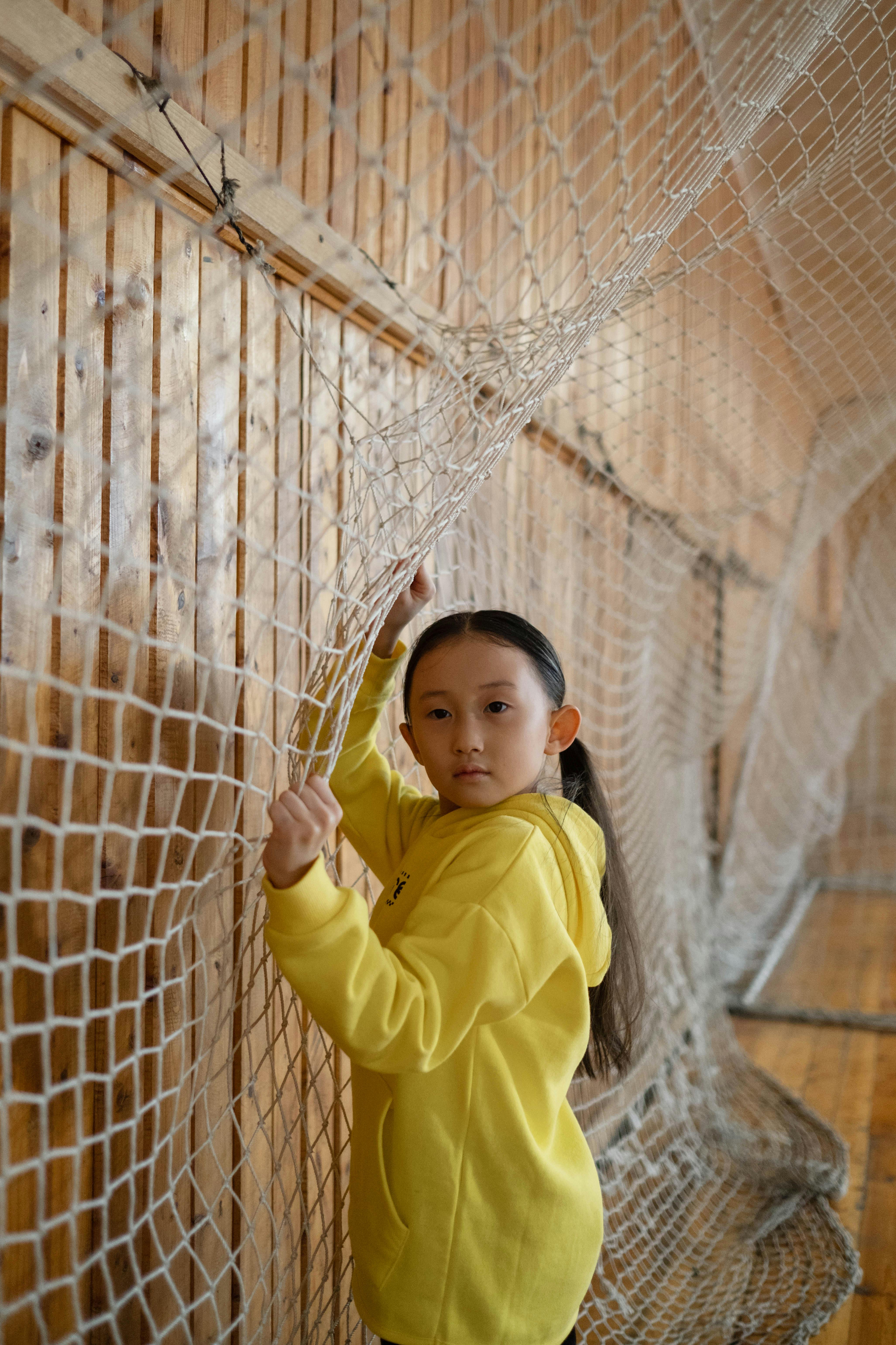 child in yellow long sleeve shirt on net