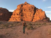 一位孤独的冒险家徒步前往偏远沙漠中引人注目的红色砂岩悬崖，捕捉冒险与孤独的本质