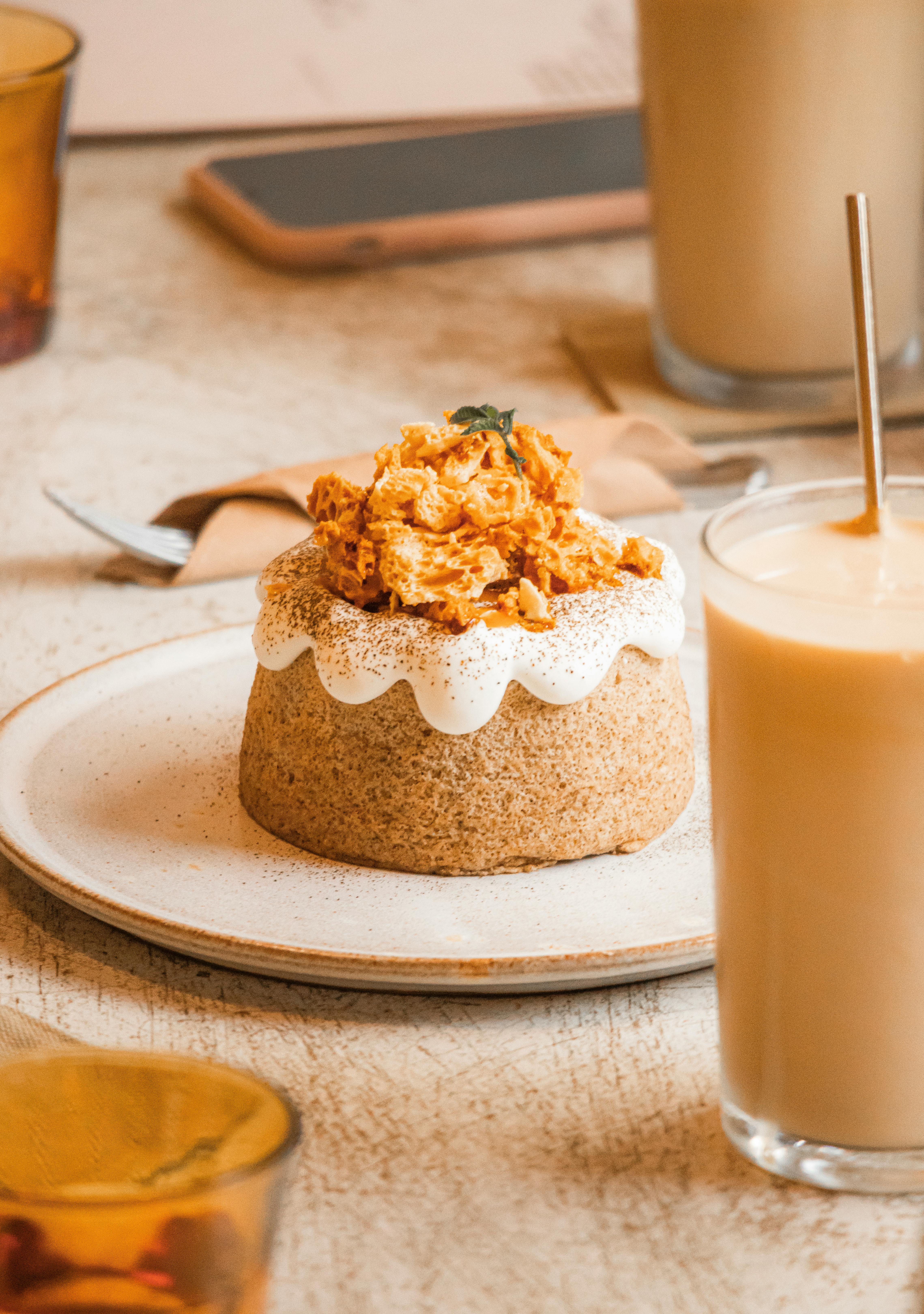 Elegant dessert with white cream and crumble on a ceramic plate, paired with a creamy drink.