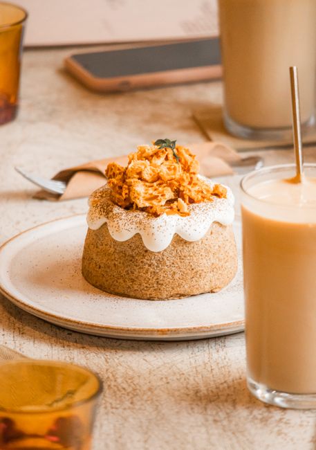 Elegant dessert with white cream and crumble on a ceramic plate, paired with a creamy drink.