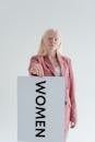 Woman in Pink Blazer Holding White and Black Box