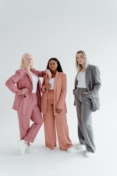 Three diverse women confidently posing in pastel suits on a white background.