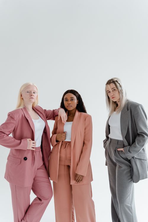 Free Three diverse women in elegant blazers posing confidently against a white backdrop. Stock Photo