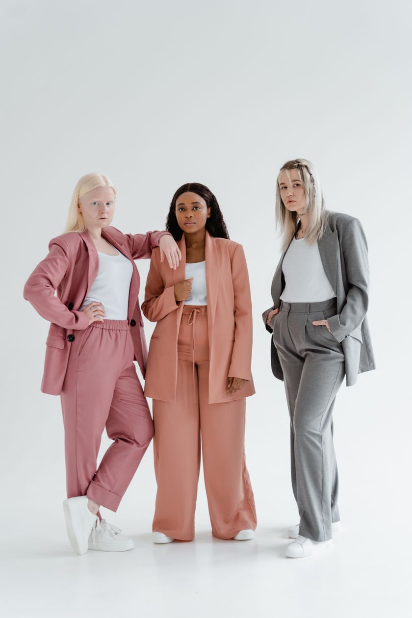 Three matching jacket-and-trouser suits worn standing side by side in a studio