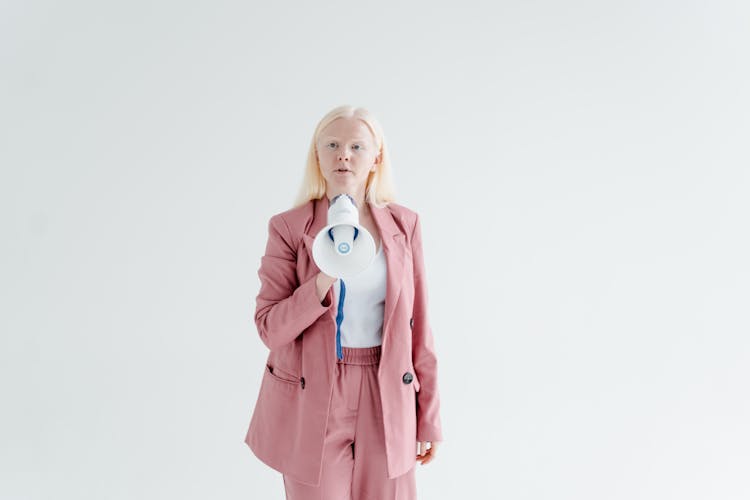 A Woman In Pink Blazer Holding A Megaphone