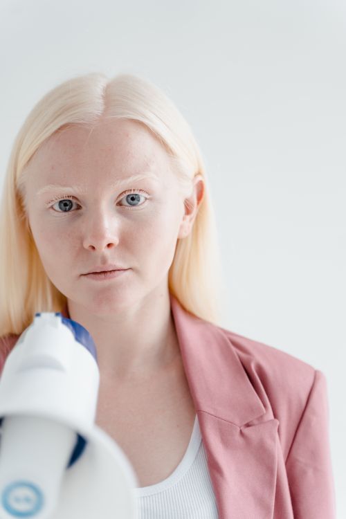 Free A woman in a pink blazer faces the camera, holding a megaphone in a studio setting. Stock Photo