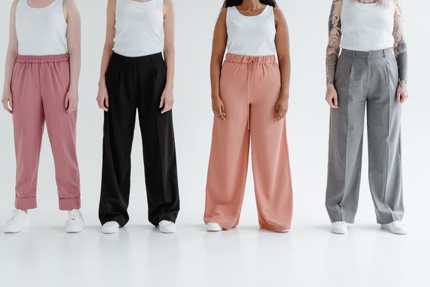 Four pairs of wide-leg trousers worn standing side by side against a plain wall