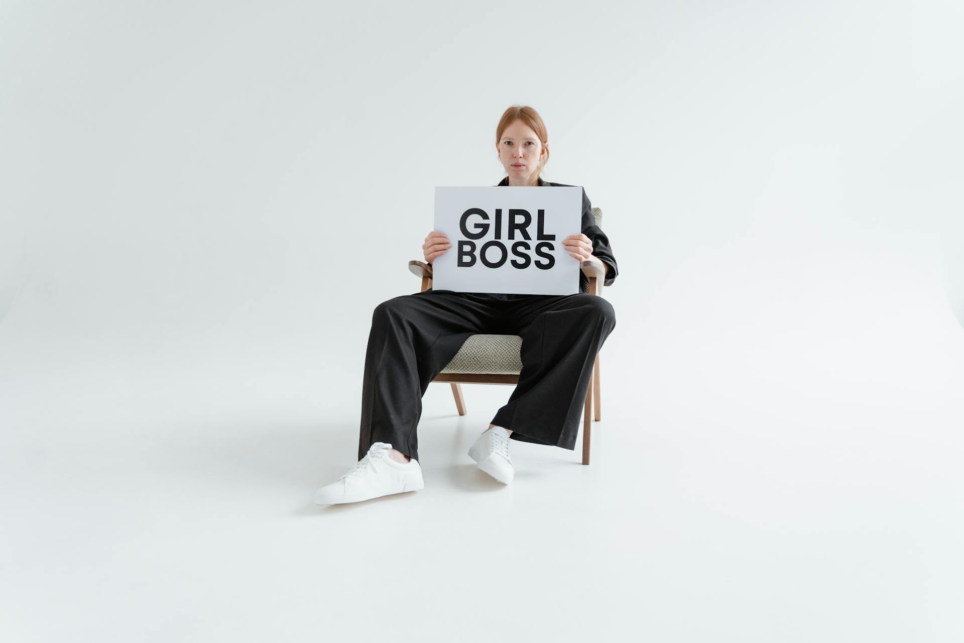 Woman Sitting While Holding a Girl Boss Postcard