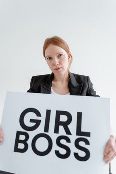 Portrait of a confident woman holding a 'Girl Boss' sign, emphasizing empowerment and leadership.