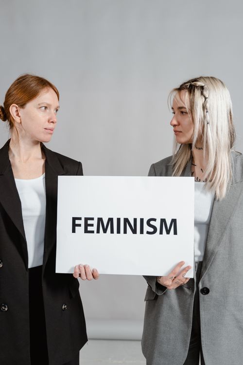 Free Two women in business attire holding a feminism sign, promoting empowerment and gender equality. Stock Photo
