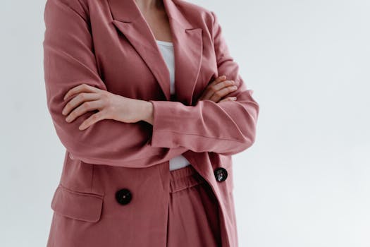 Close-up of a woman in a pink blazer with arms crossed, conveying confidence.