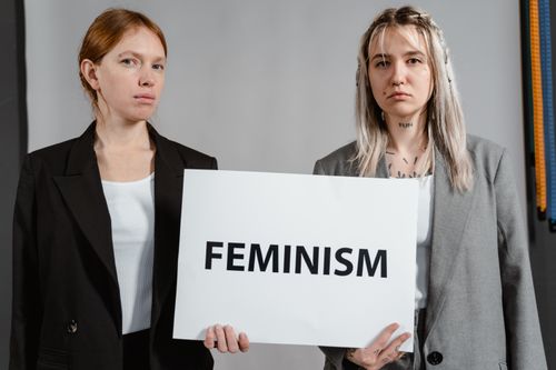 Free Two women in blazers holding a sign advocating feminism and empowerment. Stock Photo